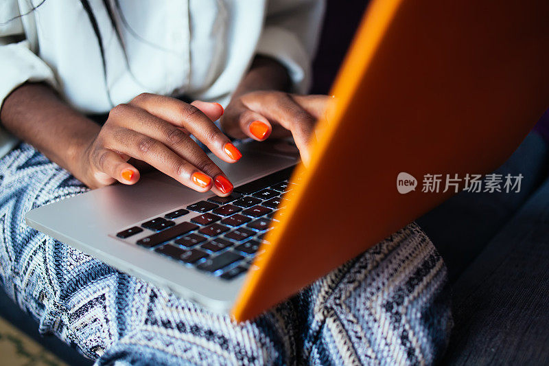 Cropped image of female blogger typing text on laptop computer working remotely on freelance, dark skinned womanâs hand with orange trendy nail polish on model netbook during job